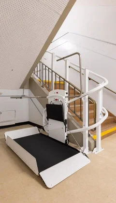 Curved rail wheel chair lift at the bottom landing beneath a stairwell.