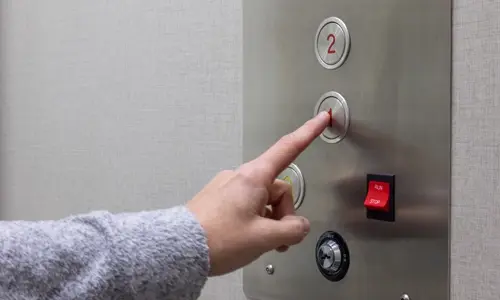 User activating first floor button on the cab operating panel.