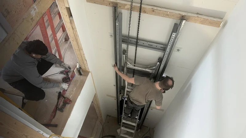 2 Elevator technicians working in the hoistway of elevator installation.