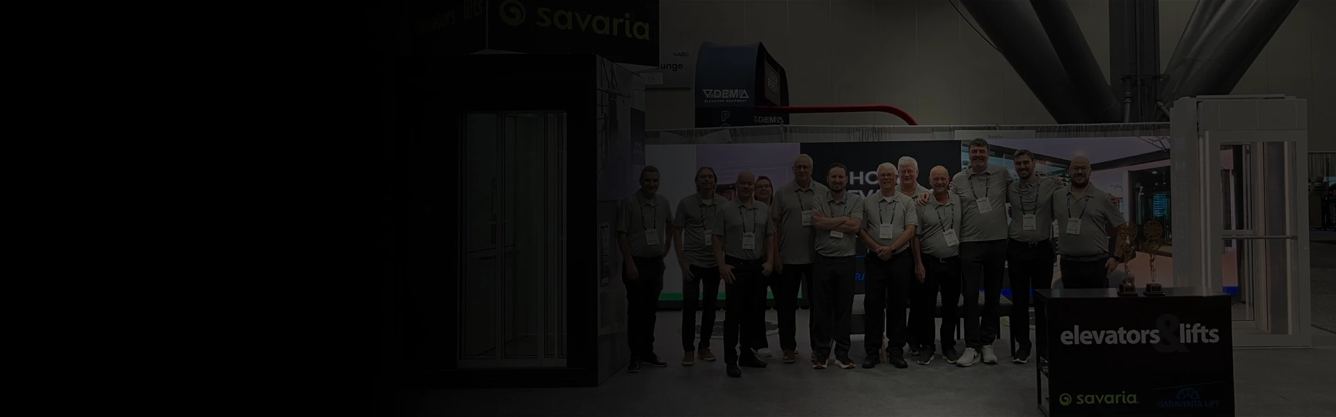 Tradeshow booth featuring home elevator and through‑the‑floor lift demos, with a team standing in front of the display.