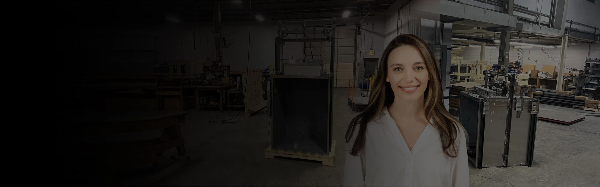 Material lift inside an industrial workshop with machinery and elevator components in the background.