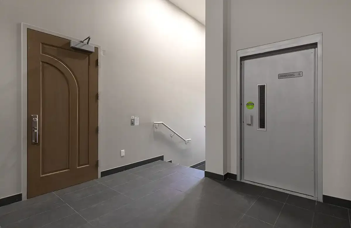 Fire-rated commercial door concealing a vertical platform lift in a modern hallway