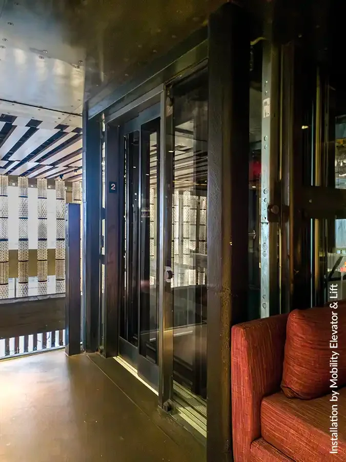 Industrial glass elevator with black metal framing in a loft-style interior