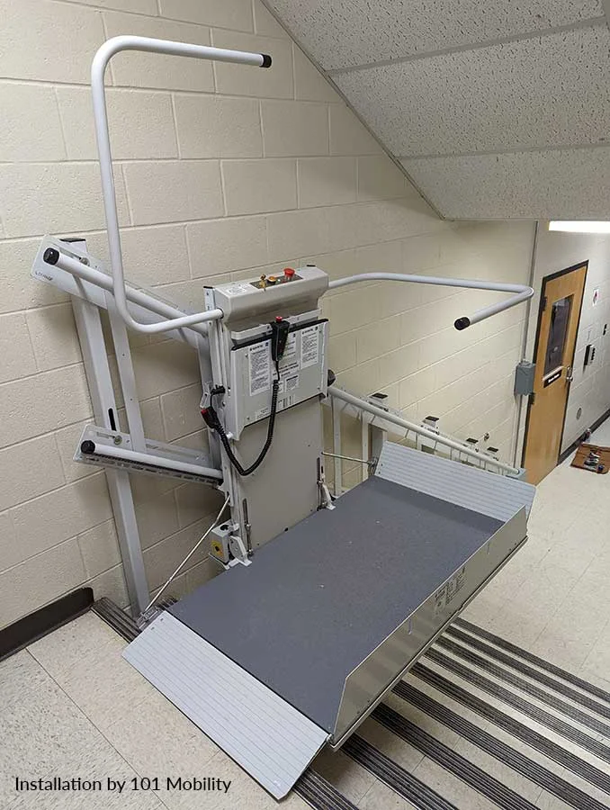 Savaria Delta inclined platform lift installed on an indoor staircase, featuring a fold‑down wheelchair platform, safety rails, and wall‑mounted rail system for commercial accessibility.