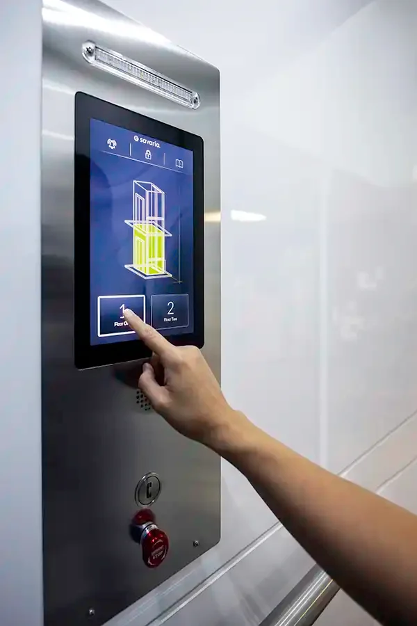 Hand interacting with a modern elevator touchscreen control panel displaying floor selection