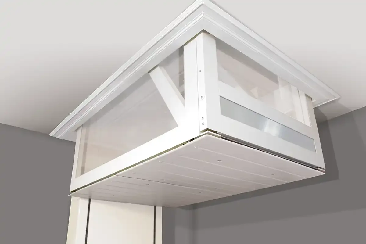 Underside of a through‑floor residential lift showing white frame, glass panels, and ceiling-mounted platform edge
