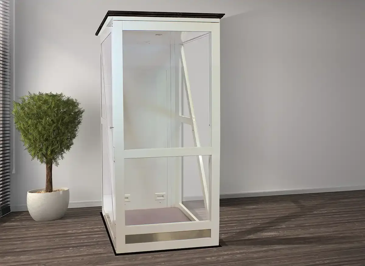 Glass residential through the floor lift with white framing, clear panels, and minimalist showroom setting