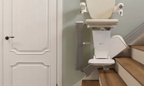 A straight stairlift track is folded so it prevents doorway obstruction.