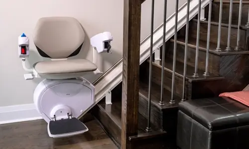 A K2 Plus straight stairlift installed next to a dark brown staircase.