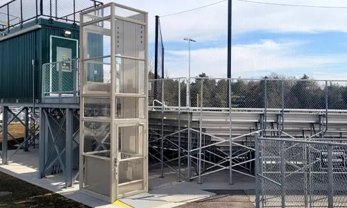 An enclosed V-1504 vertical platform lift providing accessibility to bleachers.