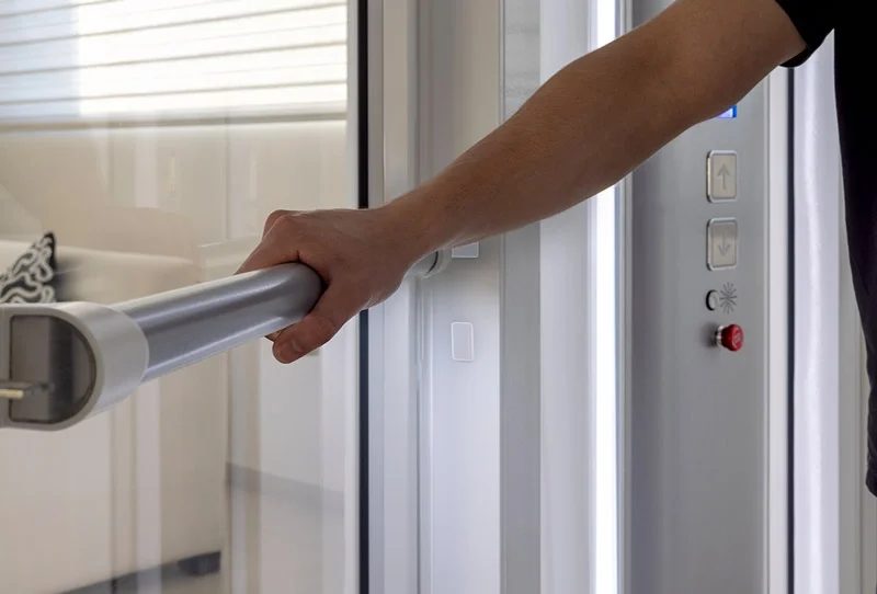 A person is exiting the Savaria Luma through the floor lift using the handrail on the full sized door.