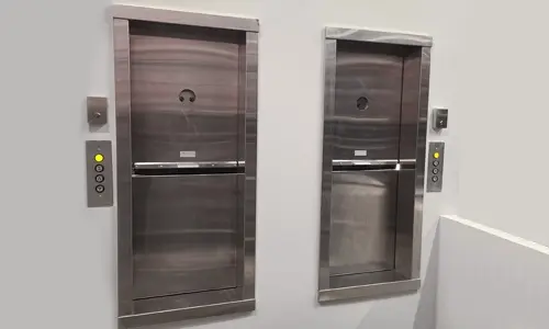 2 stainless steel dumbwaiters side by side in commercial space.