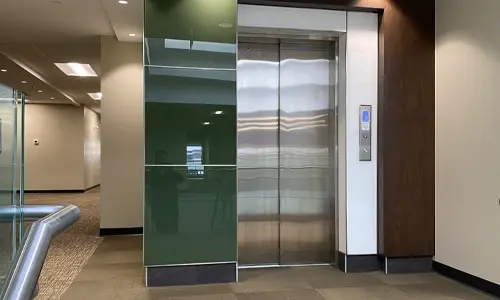 Modern elevator with stainless steel doors installed in a commercial building lobby.