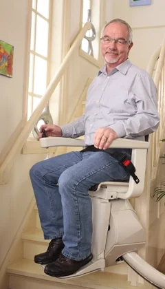 A smiling man ascending on a Freecurve stairlift.
