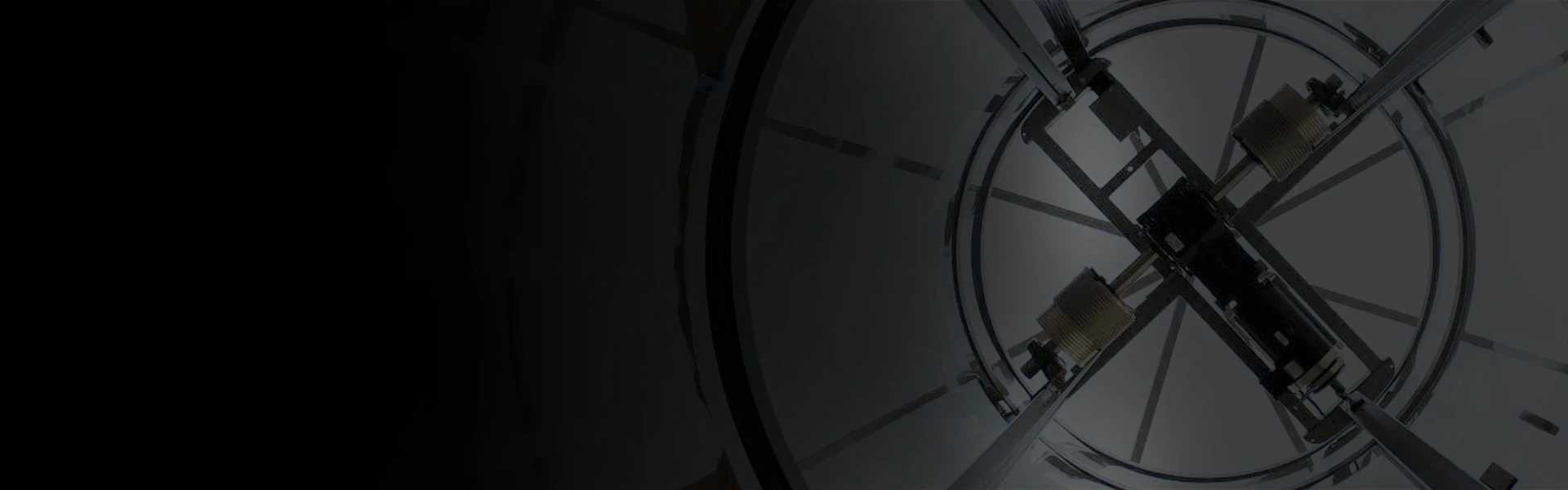 Fade to black view of the winding drum mechanism above a panoramic elevator.